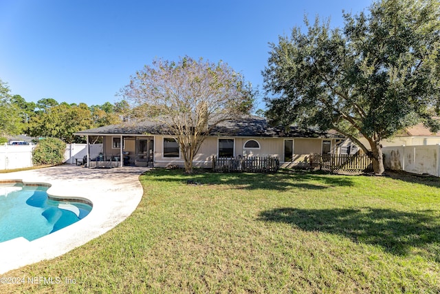 rear view of house with a fenced in pool, a yard, and a patio