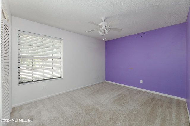 carpeted spare room featuring ceiling fan and a textured ceiling