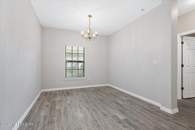 empty room featuring a chandelier and wood-type flooring