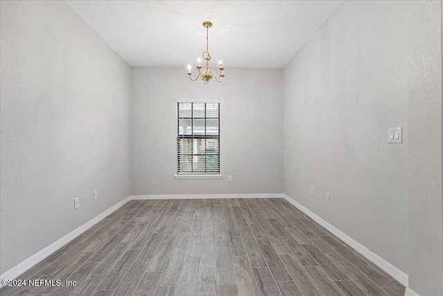 empty room featuring hardwood / wood-style floors and a chandelier