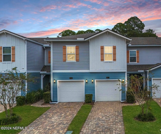 view of property featuring an attached garage, decorative driveway, and board and batten siding