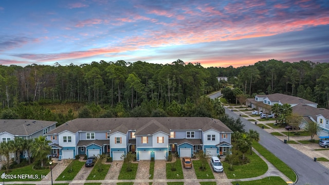 aerial view at dusk with a residential view and a wooded view