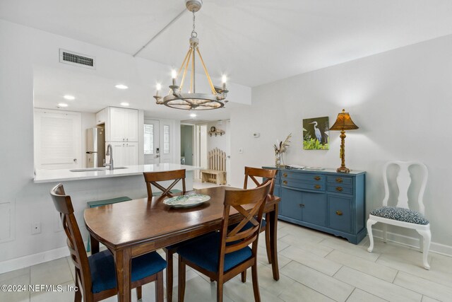 dining room featuring sink, light tile patterned flooring, and a notable chandelier