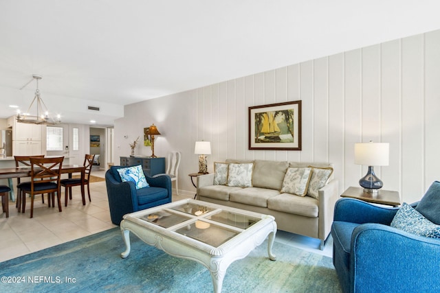 living room with a notable chandelier, wood walls, and light tile patterned floors