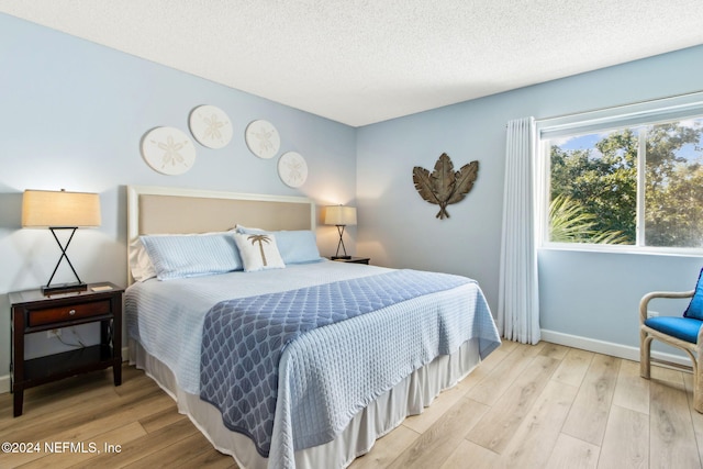 bedroom with a textured ceiling and light wood-type flooring