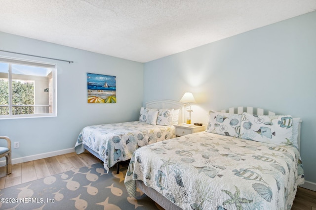 bedroom with dark hardwood / wood-style floors and a textured ceiling