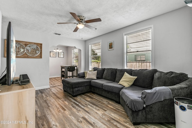 living room with hardwood / wood-style floors, ceiling fan with notable chandelier, and a textured ceiling