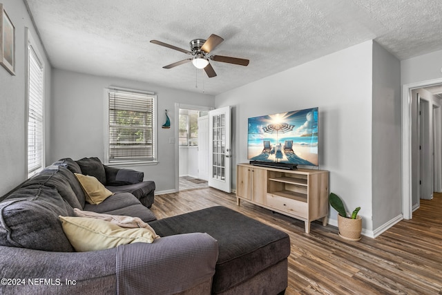 living room with dark hardwood / wood-style floors, ceiling fan, and a textured ceiling