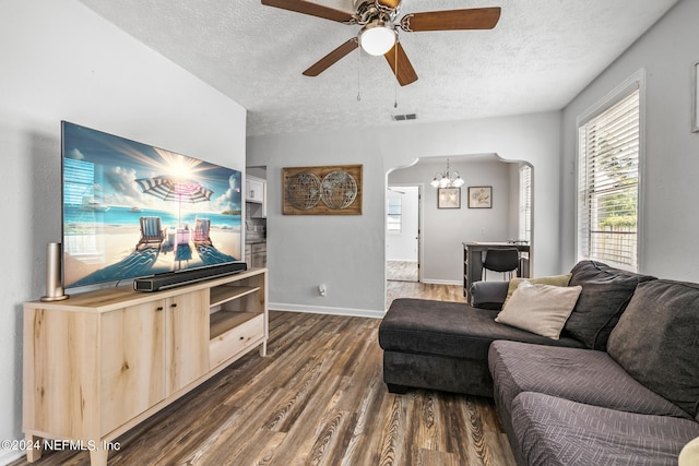 living room featuring a textured ceiling, dark wood-type flooring, and ceiling fan with notable chandelier