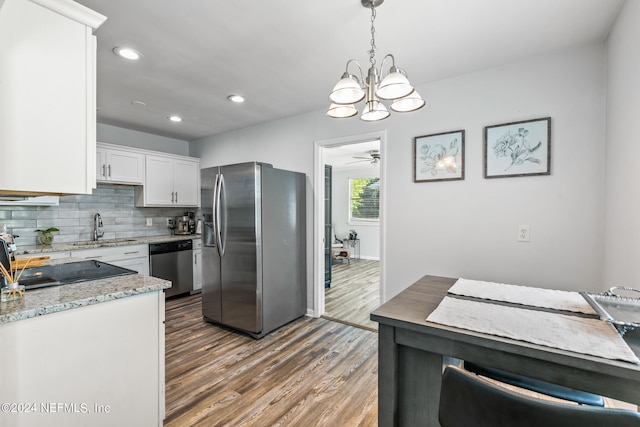 kitchen with hanging light fixtures, stainless steel appliances, dark hardwood / wood-style flooring, white cabinets, and ceiling fan with notable chandelier