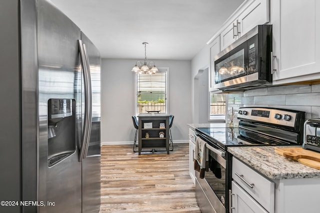 kitchen with light hardwood / wood-style flooring, pendant lighting, a chandelier, white cabinets, and appliances with stainless steel finishes