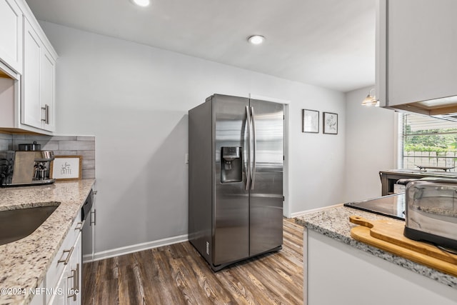 kitchen featuring light stone countertops, stainless steel fridge, decorative backsplash, dark wood-type flooring, and white cabinetry