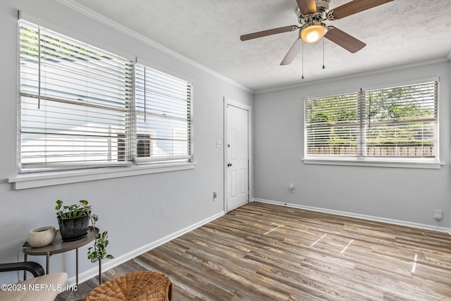 spare room featuring wood-type flooring, a textured ceiling, ceiling fan, and ornamental molding