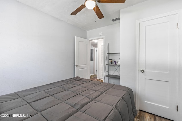 bedroom with a textured ceiling, ceiling fan, and dark hardwood / wood-style floors