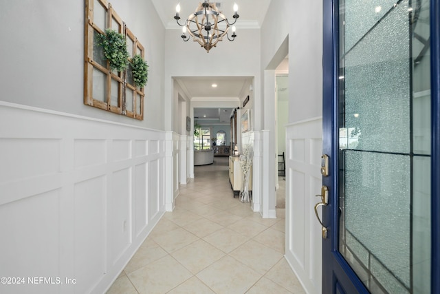 entryway featuring light tile patterned floors, an inviting chandelier, and crown molding