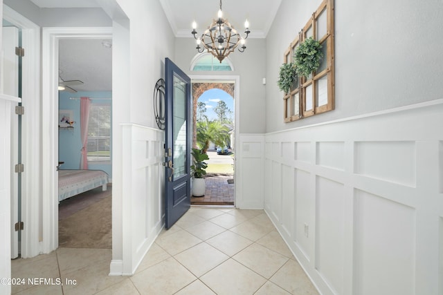 tiled entryway featuring a chandelier and ornamental molding