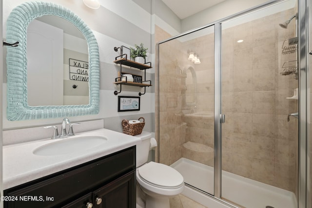 bathroom with tile patterned floors, vanity, a shower with shower door, and toilet