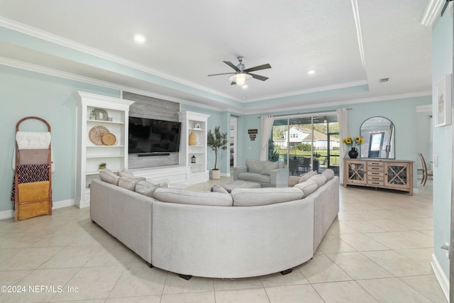 living room with a tray ceiling, ceiling fan, crown molding, and light tile patterned flooring