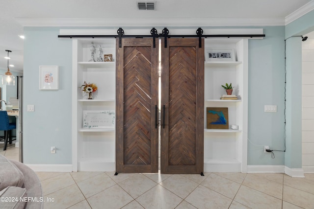 interior details with a barn door, built in features, and crown molding