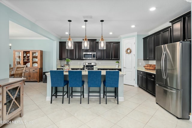 kitchen with crown molding, pendant lighting, a breakfast bar area, a kitchen island with sink, and appliances with stainless steel finishes