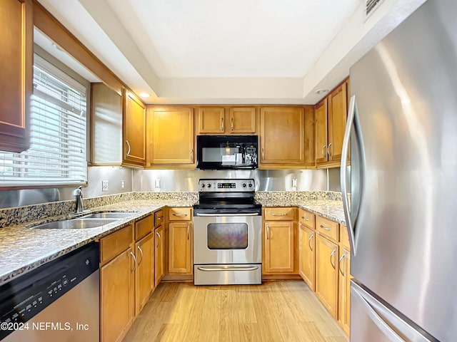 kitchen featuring sink, light stone countertops, stainless steel appliances, and light hardwood / wood-style flooring