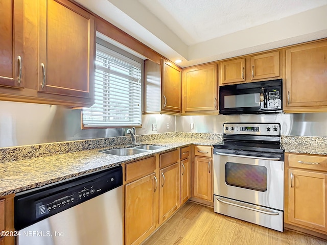 kitchen featuring light stone countertops, sink, stainless steel appliances, light hardwood / wood-style floors, and a textured ceiling