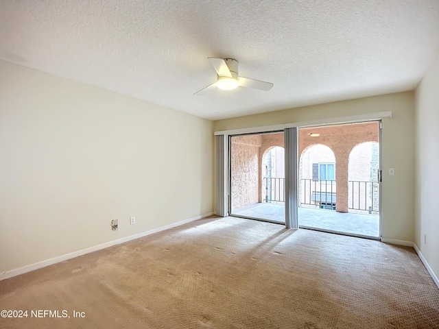 carpeted empty room featuring ceiling fan and a textured ceiling