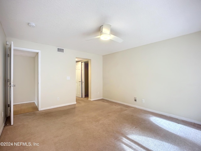 unfurnished bedroom with ceiling fan, light carpet, and a textured ceiling