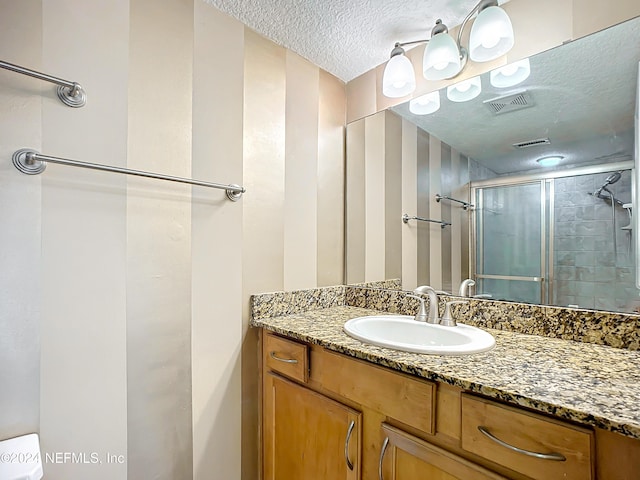 bathroom with a shower with door, vanity, and a textured ceiling