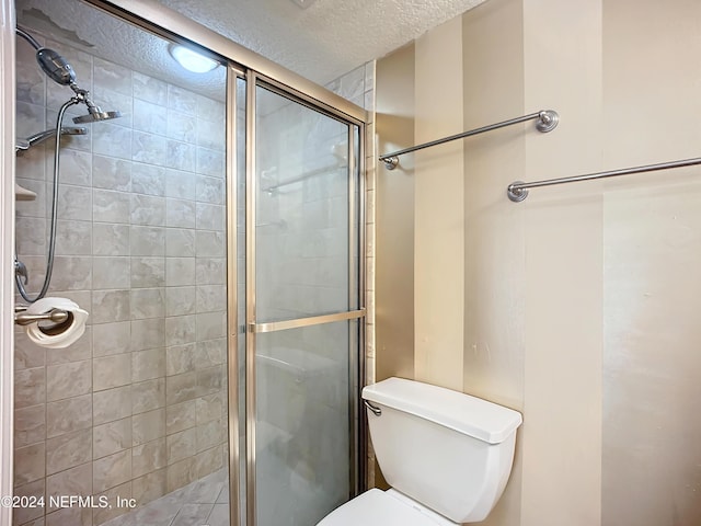 bathroom with toilet, a textured ceiling, and walk in shower