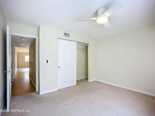 unfurnished bedroom with ceiling fan, a closet, light hardwood / wood-style floors, and a textured ceiling