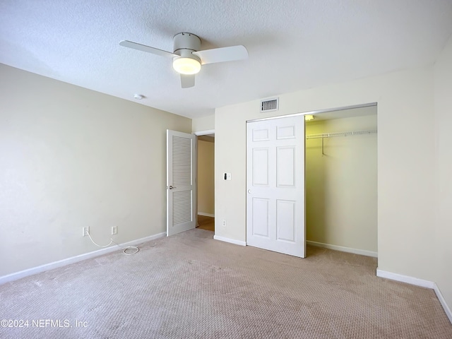 unfurnished bedroom featuring ceiling fan, a closet, light colored carpet, and a textured ceiling