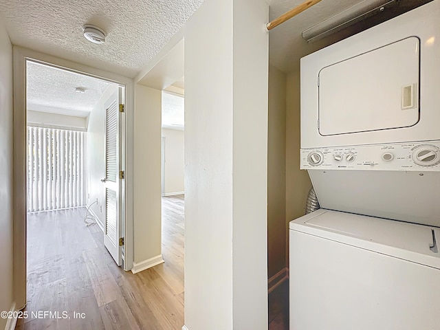 5375 Ortega Farms Blvd Unit 614, Jacksonville, FL 32210 - washroom featuring stacked washer and clothes dryer, light wood finished floors, a textured ceiling, and baseboards