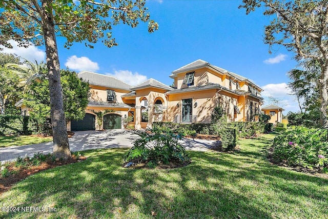 mediterranean / spanish-style home featuring stucco siding, a front yard, a garage, and driveway