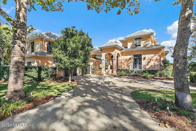 mediterranean / spanish house featuring a tile roof, decorative driveway, a garage, and stucco siding