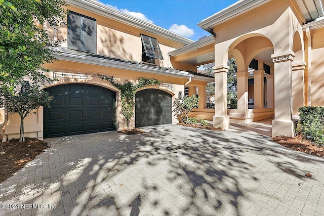 view of front facade with decorative driveway, a garage, and stucco siding