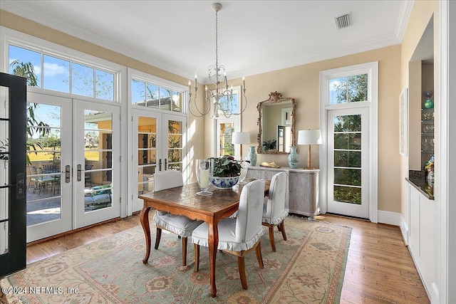 dining area with visible vents, french doors, an inviting chandelier, crown molding, and light wood finished floors