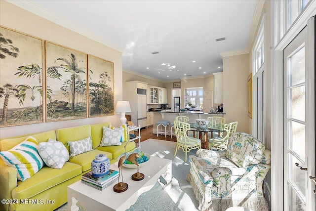 living room with crown molding, wood finished floors, and visible vents