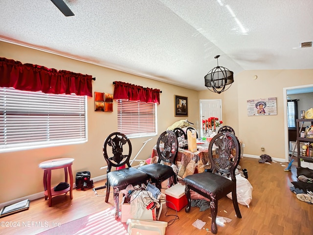 interior space featuring a textured ceiling, a chandelier, wood-type flooring, and lofted ceiling