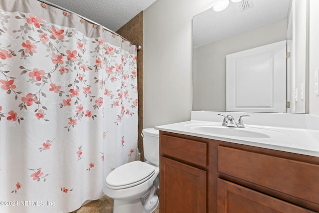 bathroom with vanity, toilet, and a textured ceiling