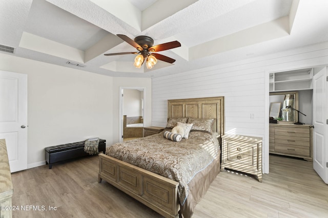 bedroom featuring a raised ceiling, light hardwood / wood-style flooring, and ceiling fan