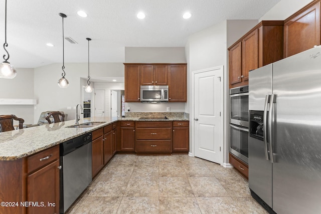 kitchen with sink, appliances with stainless steel finishes, decorative light fixtures, light stone counters, and kitchen peninsula