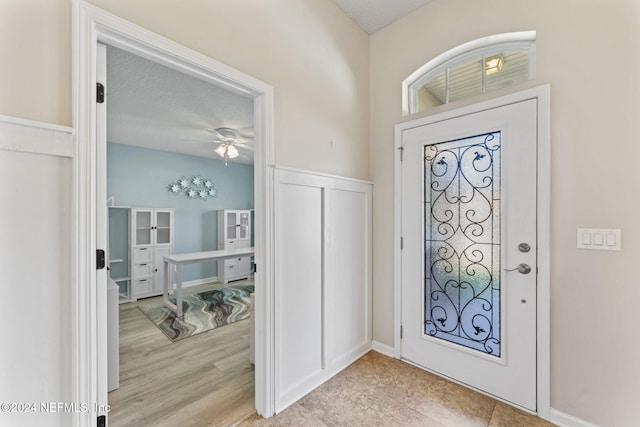 foyer entrance featuring ceiling fan, light hardwood / wood-style flooring, and a textured ceiling