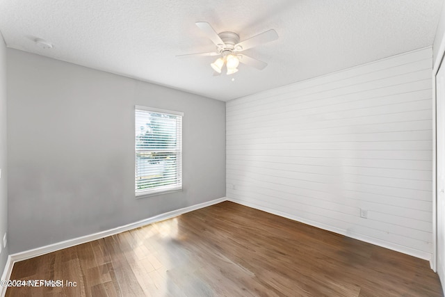 empty room with ceiling fan, wood-type flooring, and a textured ceiling