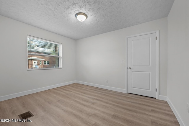 empty room featuring light wood-type flooring and a textured ceiling