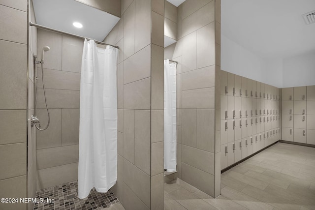 bathroom with a shower with shower curtain and tile walls