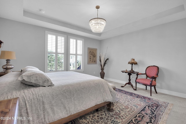 carpeted bedroom with a raised ceiling and a chandelier