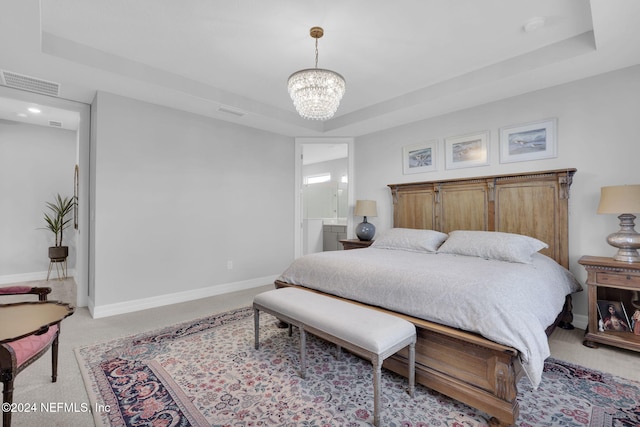 carpeted bedroom with a tray ceiling, ensuite bathroom, and a chandelier