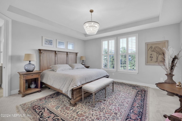 carpeted bedroom with an inviting chandelier and a raised ceiling