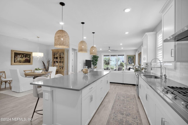 kitchen with decorative light fixtures, light hardwood / wood-style floors, white cabinetry, and sink